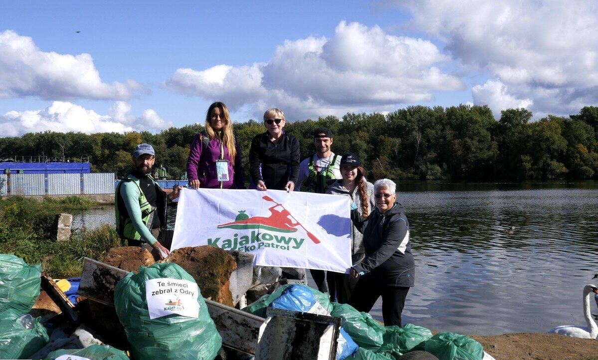 Grupa wolontariuszy z banerem Kajakowy Ekopatrol z workami śmieci zebranymi z Odry
